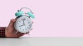 Retro styled white alarm clock in manÃ¢â¬â¢s hand, isolated, pink